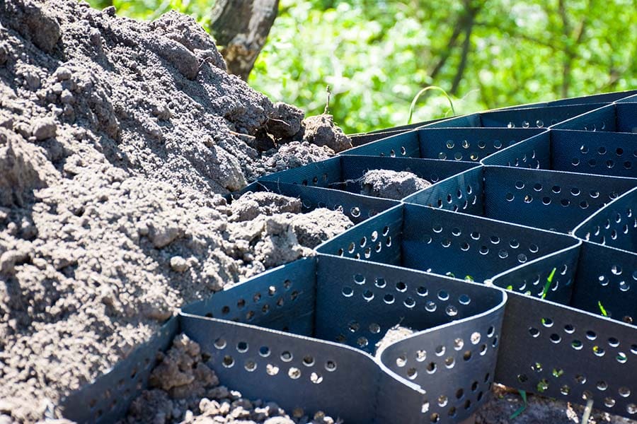 Scene of technology of strengthening the slope of a hill, mountain or ravine using plastic geogrid. Photos with an empty and already covered with soil geogrid closeup on a background with greenery