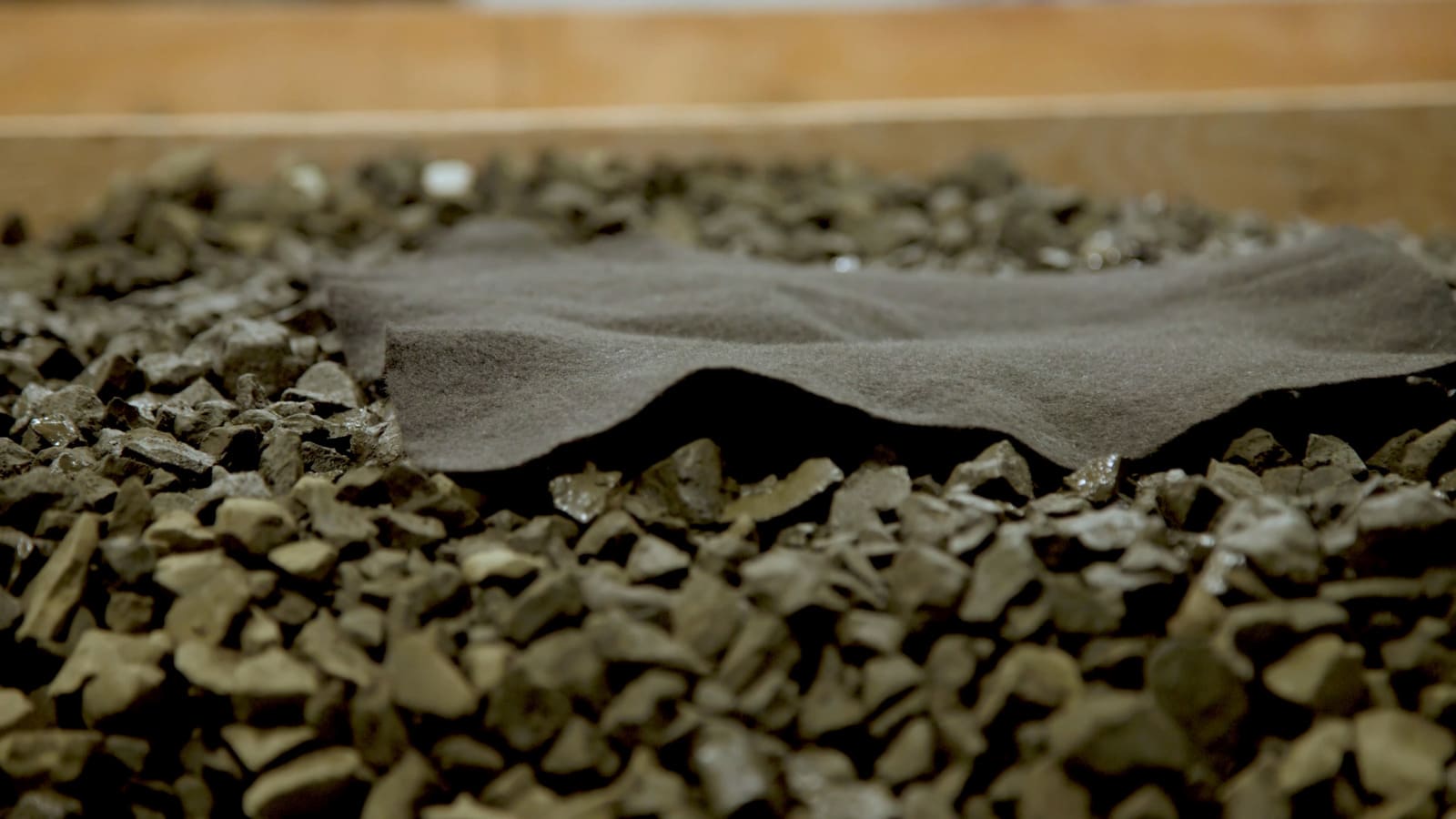 Geotextile landscape fabric used beneath decorative gravel in a professional landscape construction project