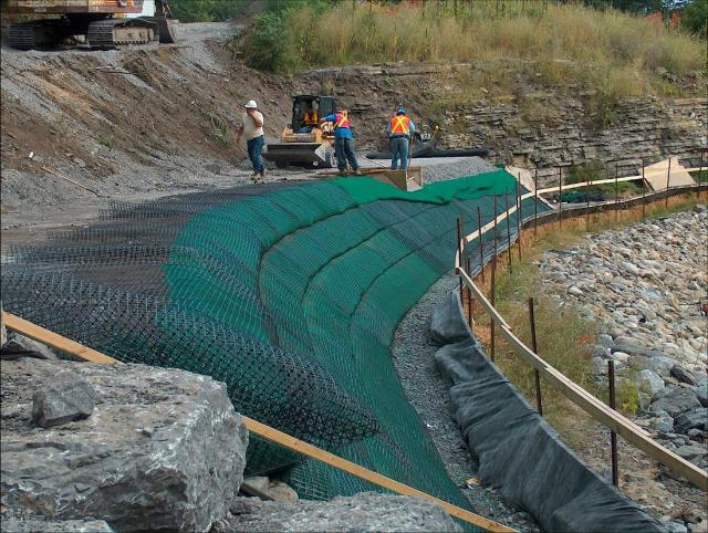 Engineers deploying geotextiles and geomembranes in a landfill site