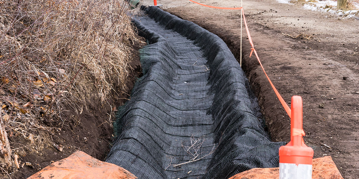Retaining wall drainage system with nonwoven filtration layer, aggregate and perforated pipe
