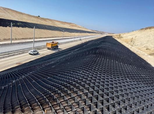 Road construction site showing geocell reinforcement system used for pavement base stabilization and load distribution