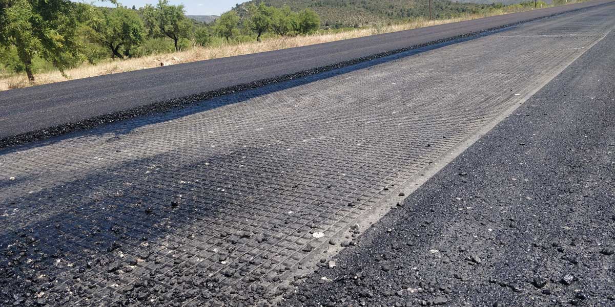 Road construction showing geosynthetics installation with geogrid and geotextile beneath aggregate layers